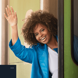 A woman waving goodbye as she gets on a train.