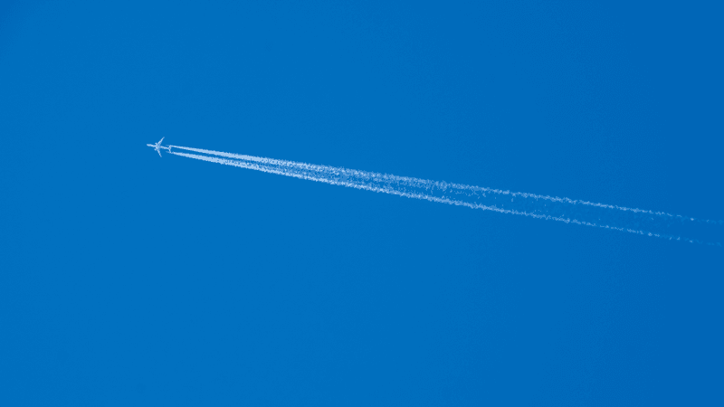 a plane leaving a white trail behind in a blue sky