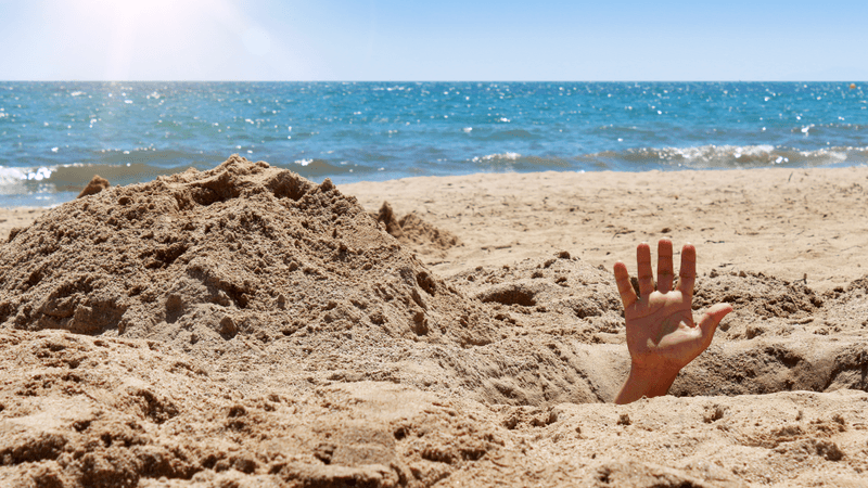 person's hand sticking out from giant hole in dry sand