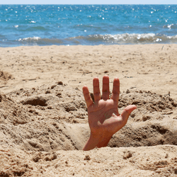 person's hand sticking out from giant hole in dry sand